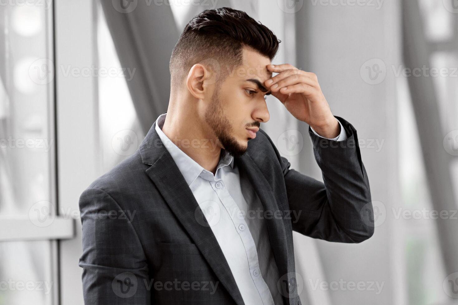 Portrait Of Thoughtful Middle Eastern Businessman Standing With Luggage At Airport Terminal, Pensive Young Arab Male Touching Forehead, Thinking About Missed Flight And Problem Solution, Copy Space photo