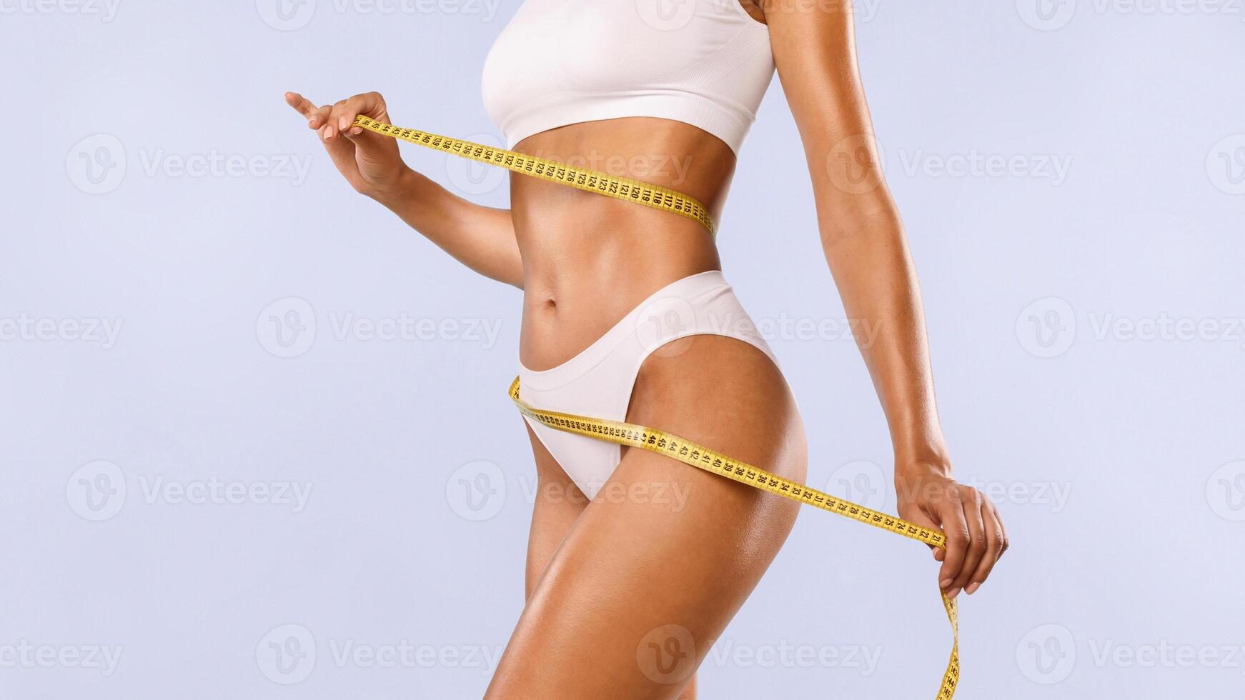 Successful Weightloss And Dieting. Closeup Of Slim Lady Measuring Waist With Tape, Happy About Her Body Parameters, Standing Isolated Over Blue Studio Background. Slimming Concept. Banner photo