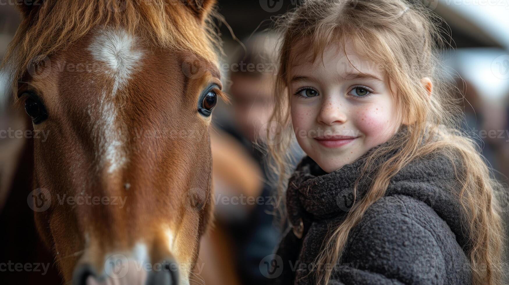 A smiling girl stands beside a brown horse at a stable in the countryside. She wears a cozy jacket and enjoys a pleasant afternoon, showcasing the joyful connection with her horse. photo