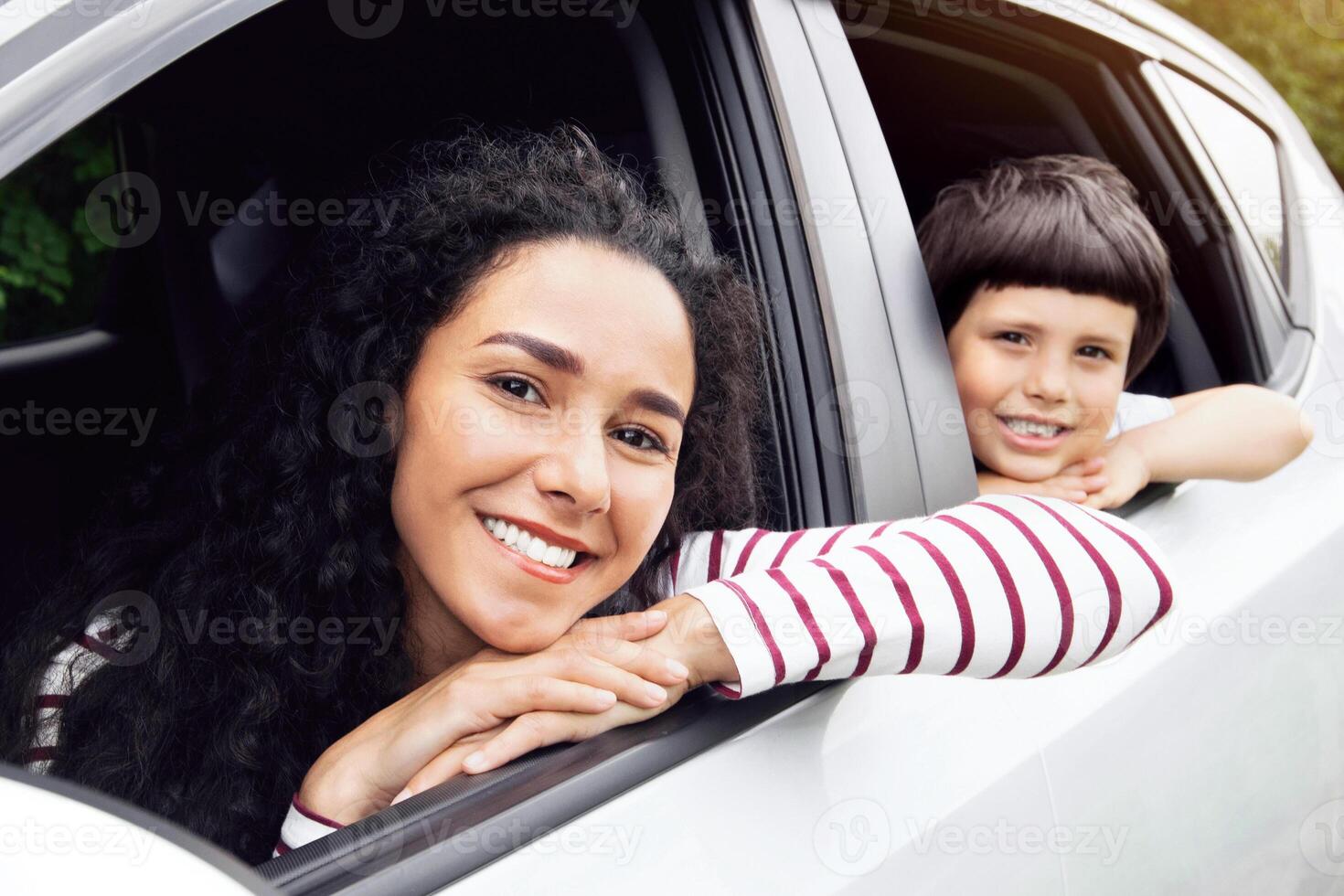 Road Trip. Happy Young Family With Little Son Riding Car Together, Cheerful Mother And Male Child Looking Out Of Windows And Smiling At Camera, Enjoying Automobile Outdoor Travels, Closeup Shot photo