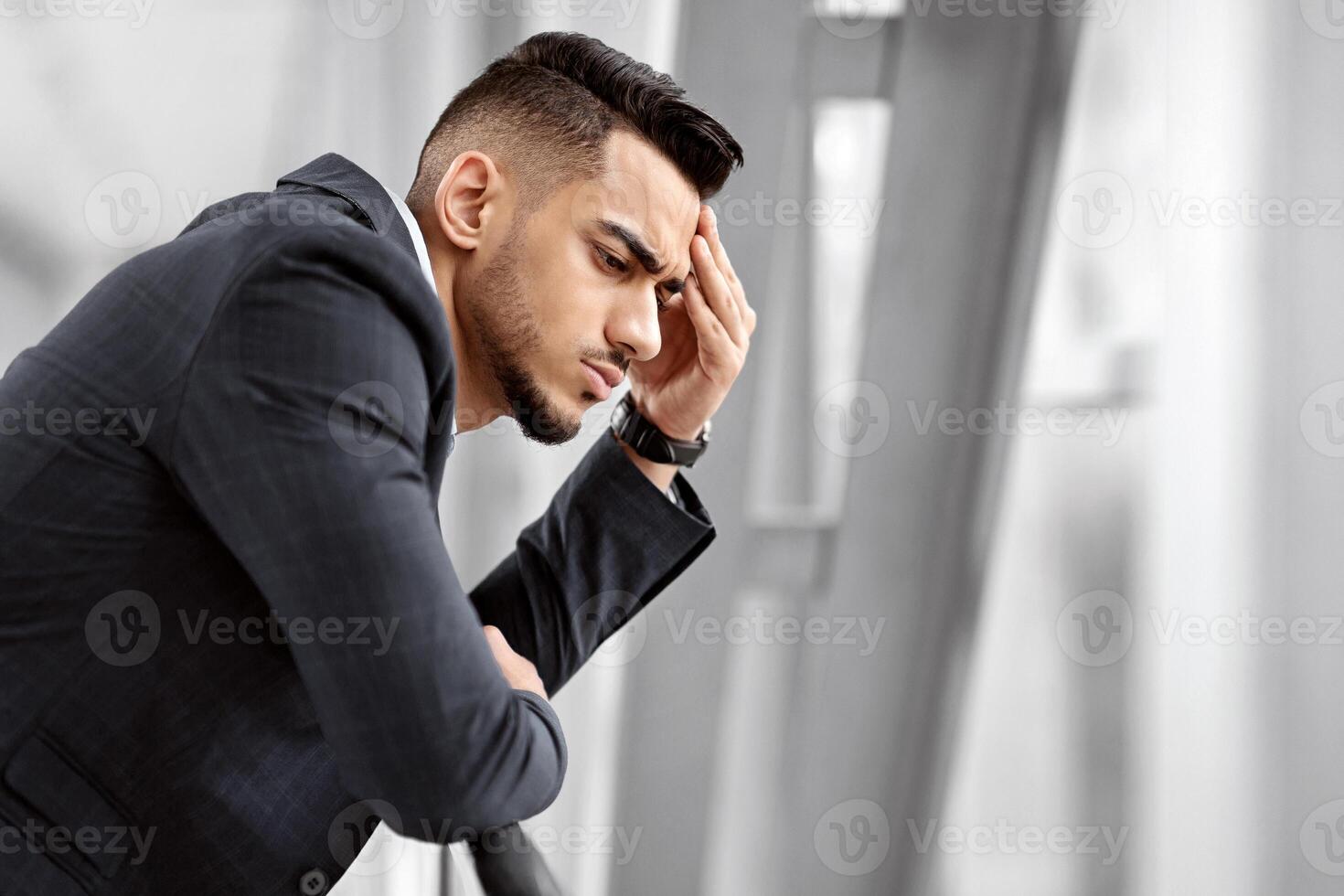 Portrait Of Pensive Middle Eastern Man In Suit Standing Near Window At Airport Terminal, Thoughtful Arab Businessman Waiting For Flight In Lounge, Having Business Problems Or Suffering From Headache photo