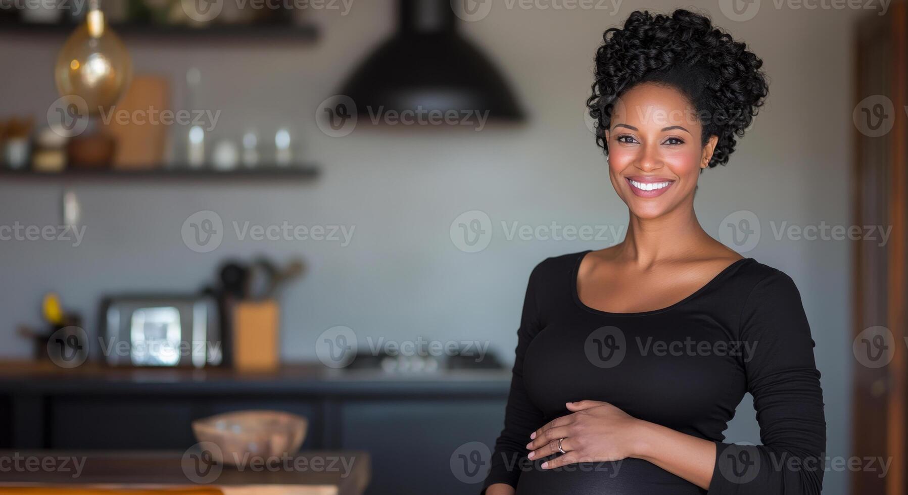 A pregnant woman stands in her modern kitchen with a warm smile. She gently cradles her baby bump while surrounded by a cozy, inviting atmosphere filled with natural light. photo