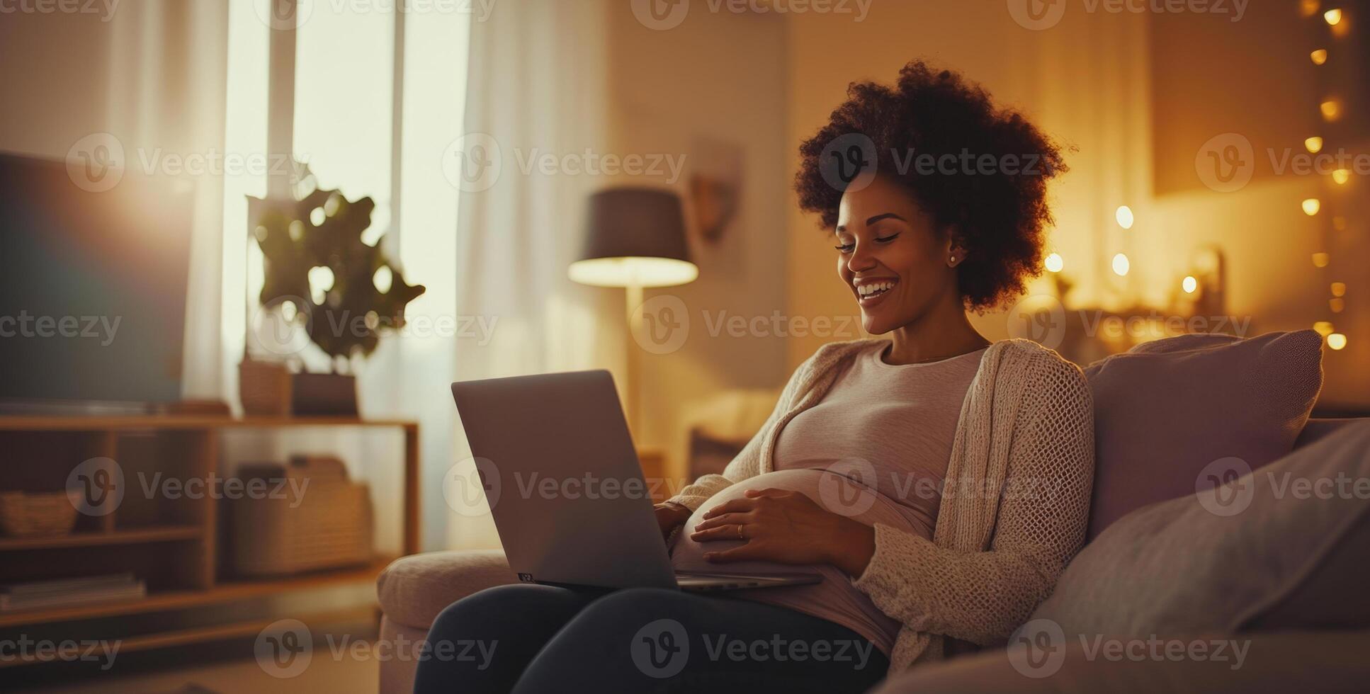 A pregnant woman is sitting on a comfortable sofa in a softly lit living room, happily using her laptop. It is evening, and warm light filters through the windows, creating a cozy atmosphere. photo