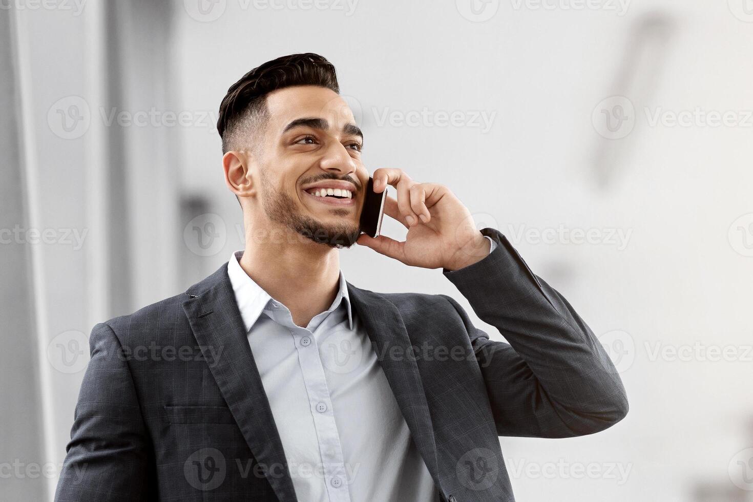 Business Trip. Smiling Arab Male Entrepreneur Holding Digital Tablet And Talking On Cellphone While Walking At Airport Terminal, Middle Eastern Businessman Enjoying Mobile Conversation, Copy Space photo