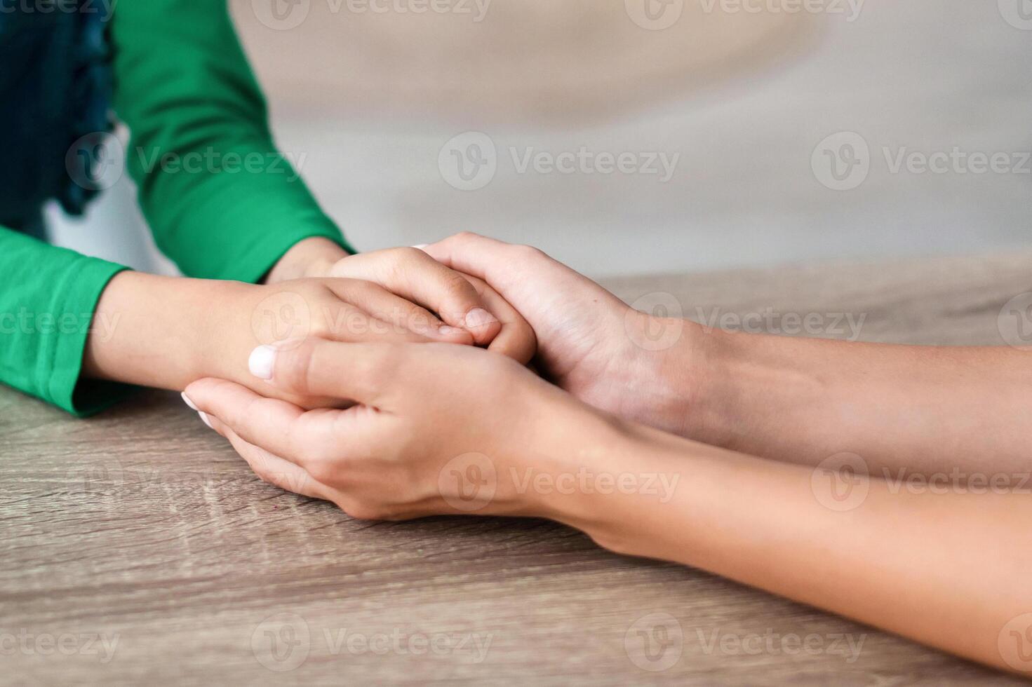 Trust, Love And Support Concept. Cropped close up of unrecognizable woman and girl holding hands, enjoying spending free time together, sitting at desk. Children Custody And Family Care photo