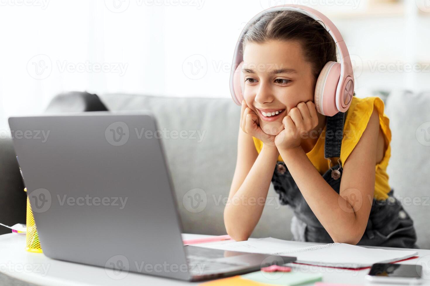 Distance Learning. Cute little home schooler girl having lesson using laptop in living room, studying with computer, enjoying online education, listening to teacher photo