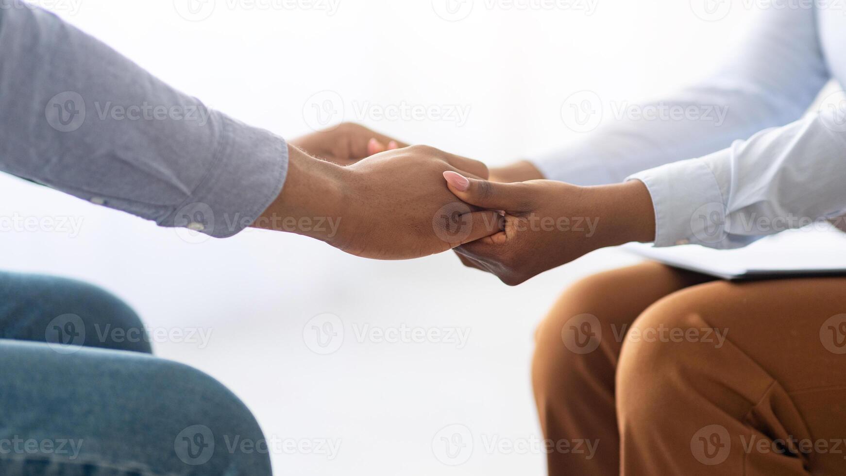 Professional support. Psychotherapist helping stressed male patient, holding his hands at mental clinic, closeup. Unrecognizable psychologist comforting young man with depression, cropped view photo