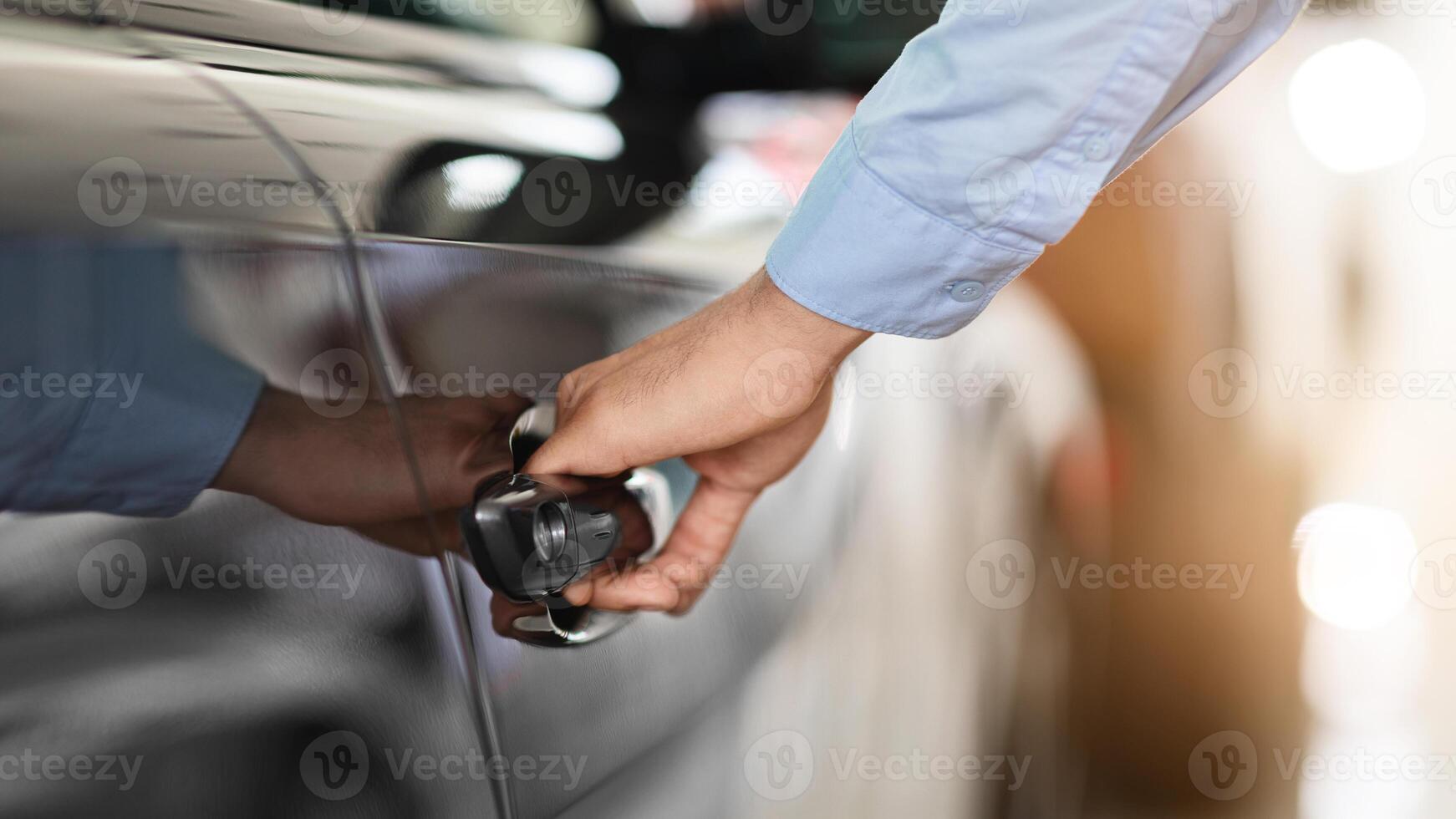 Cropped of man open car door, closeup of male hand with watch unlocking black auto door, making test drive at newest automobile showroom. Vehicle, transportation, car salon concept photo