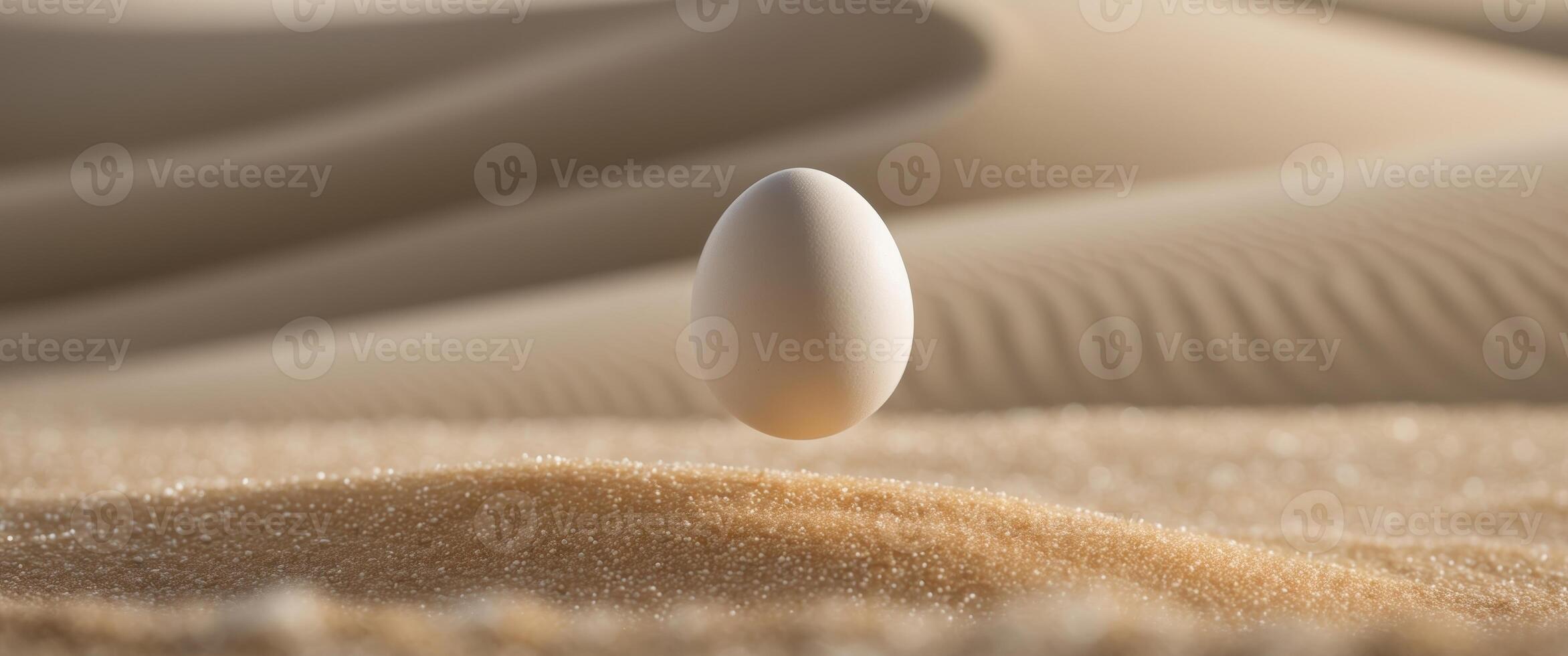 A close up of an egg falling into the sand. photo