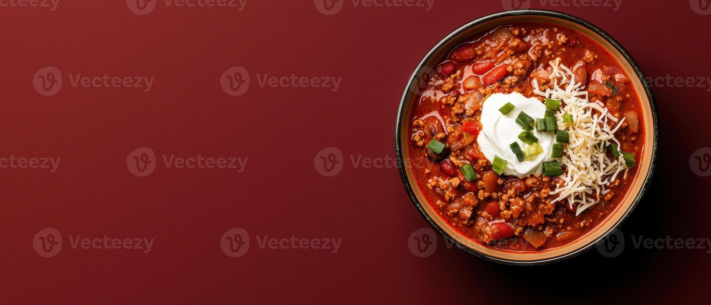 A bowl of hearty chili topped with sour cream and cheese. photo