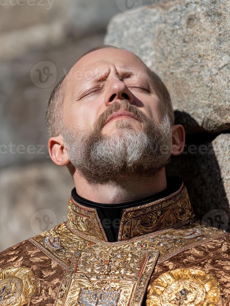 Man in ornate gold religious robe with eyes closed photo