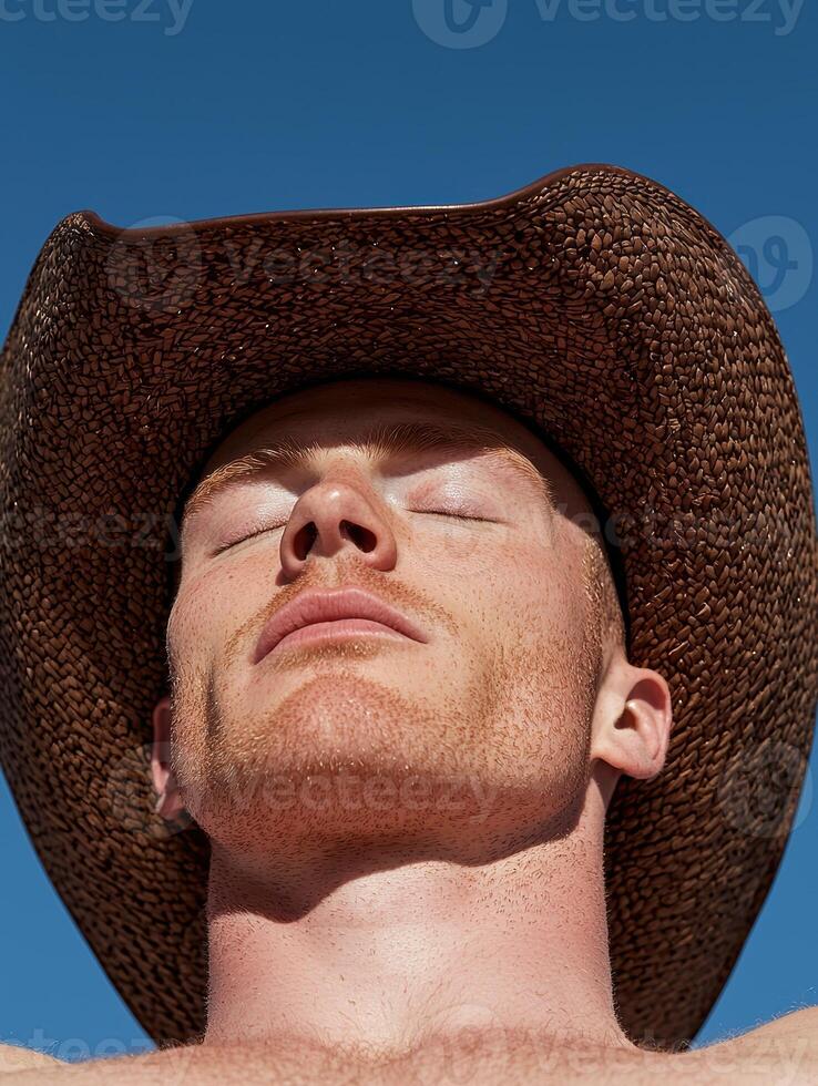 Redhead man sunbathing under a brown cowboy hat photo