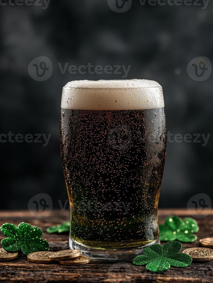 Close up of a glass of dark beer with shamrocks and coins on a wooden table photo