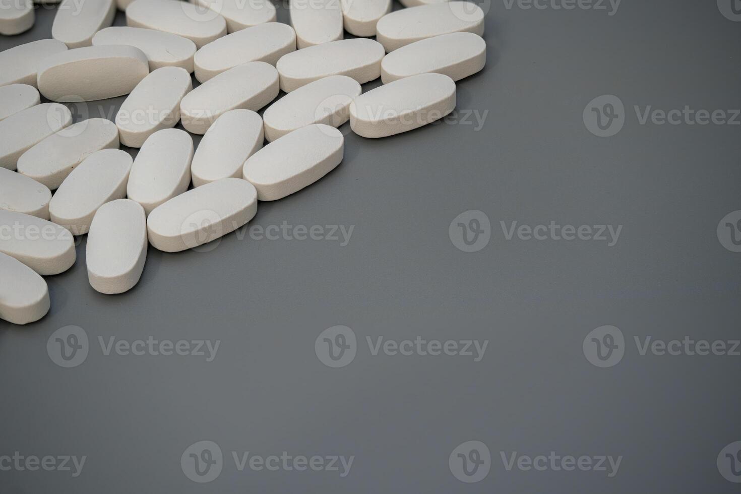White tablets scattered on a gray surface with neutral lighting photo