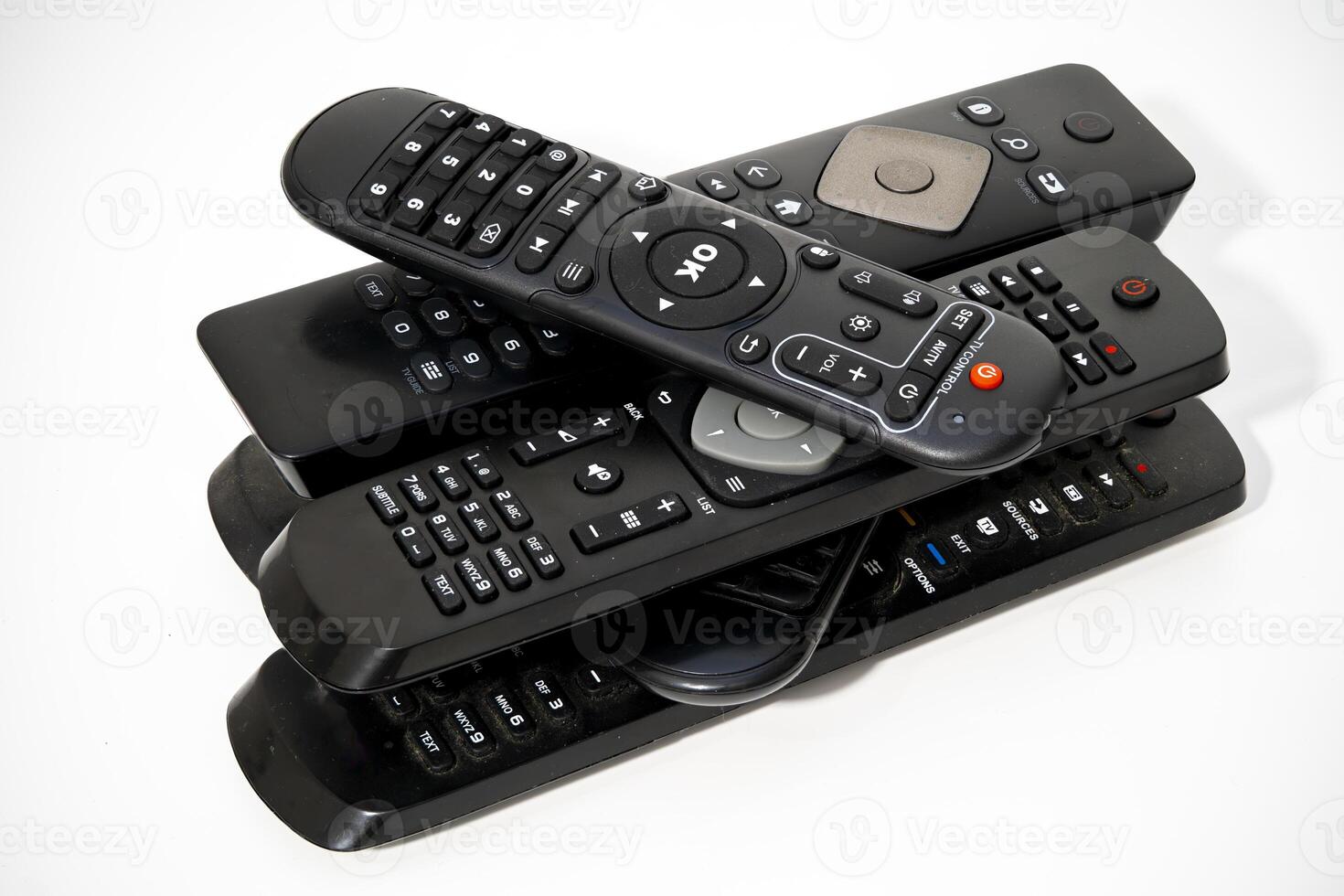 Collection of remote controls piled together on a white background photo