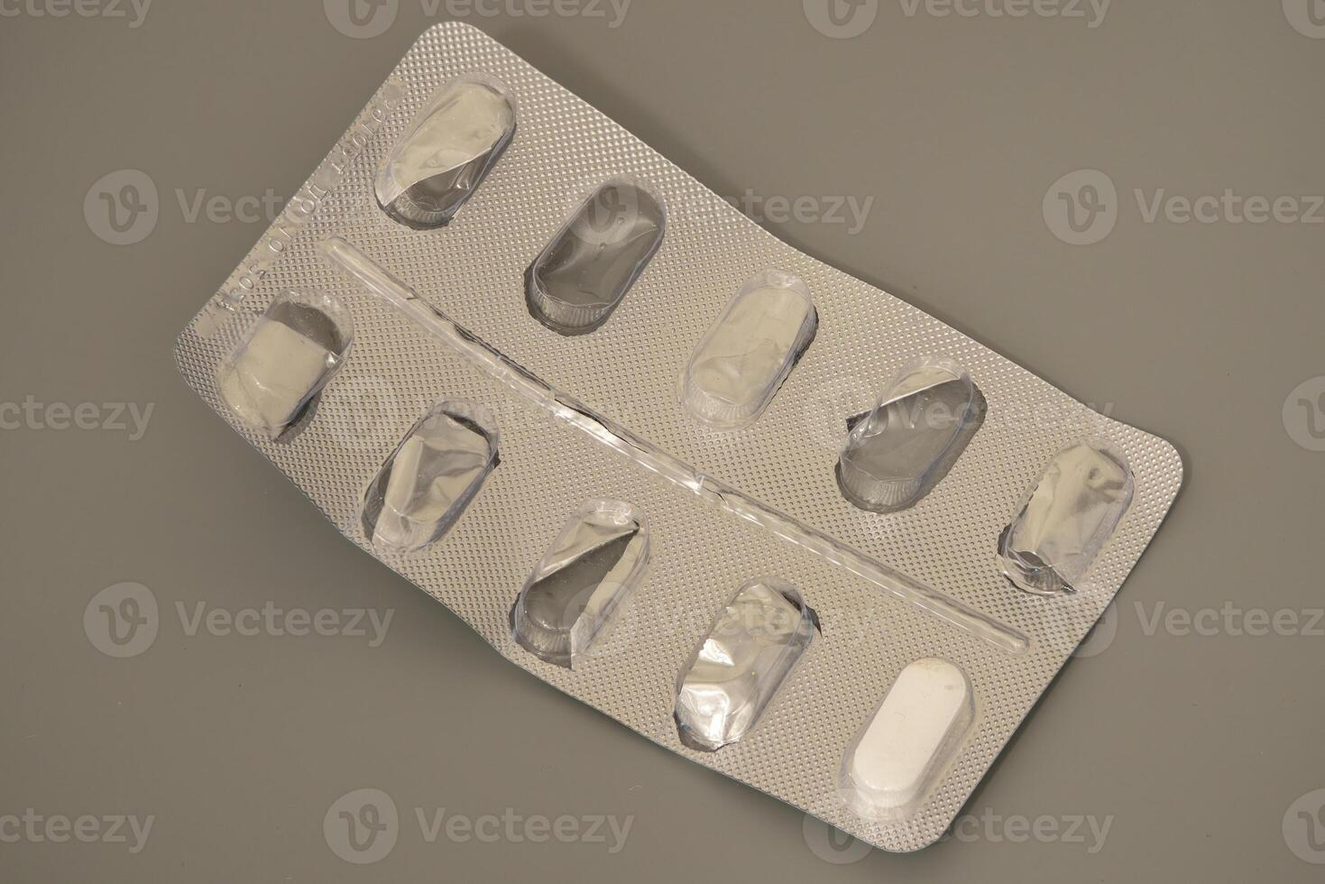 Pill blister pack with missing tablets on gray background photo