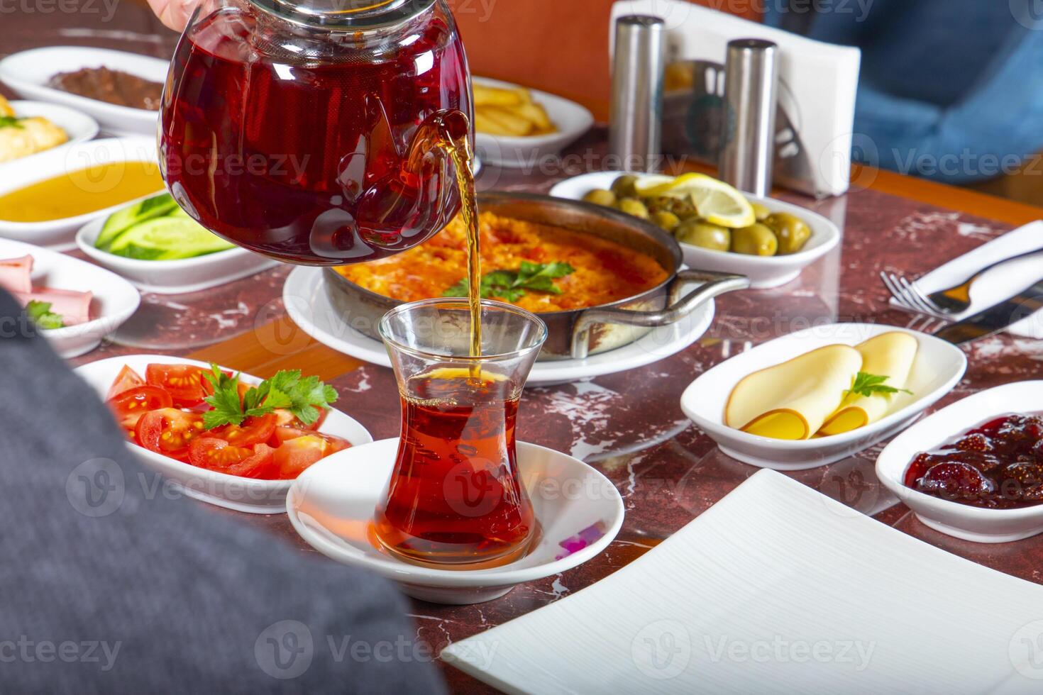 Pouring hot tea at a vibrant dining table with various dishes photo