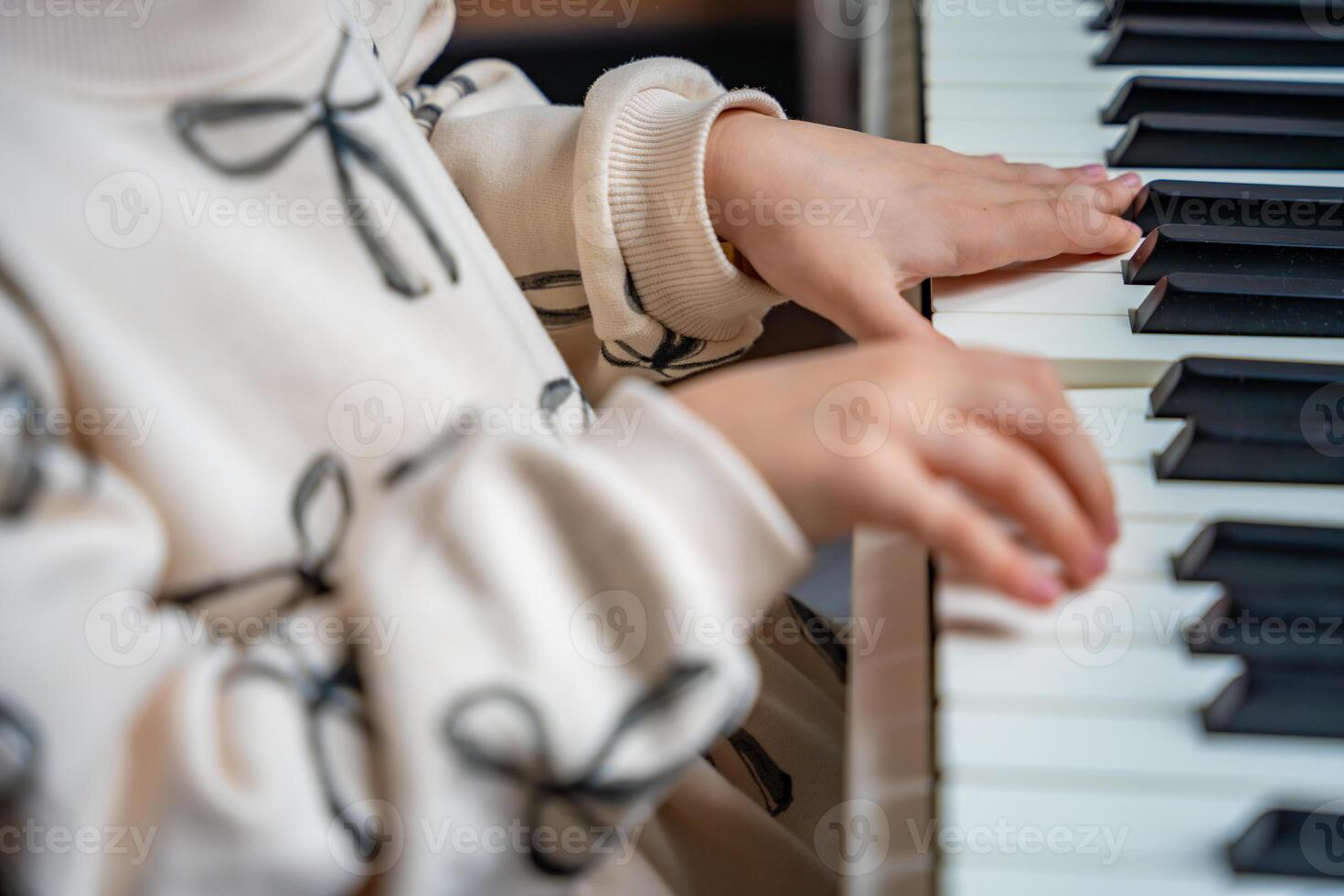 Close up view of small hands of girl on white piano synthesizer. Concept of early development. learning music enhances motor skills, hearing, and intelligence, fostering creativity from childhood. photo
