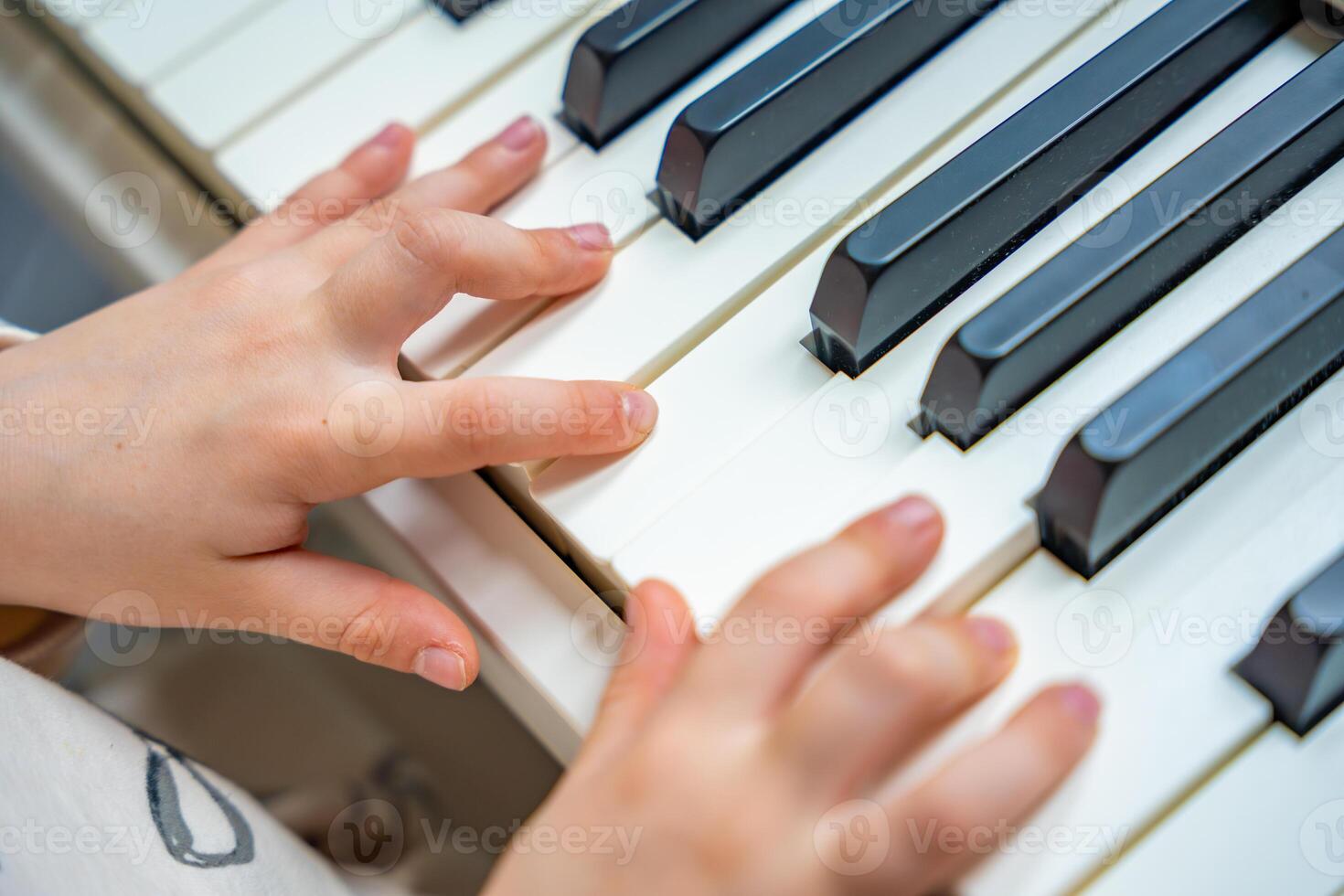Close up view of small hands of girl on white piano synthesizer. Concept of early development. learning music enhances motor skills, hearing, and intelligence, fostering creativity from childhood. photo