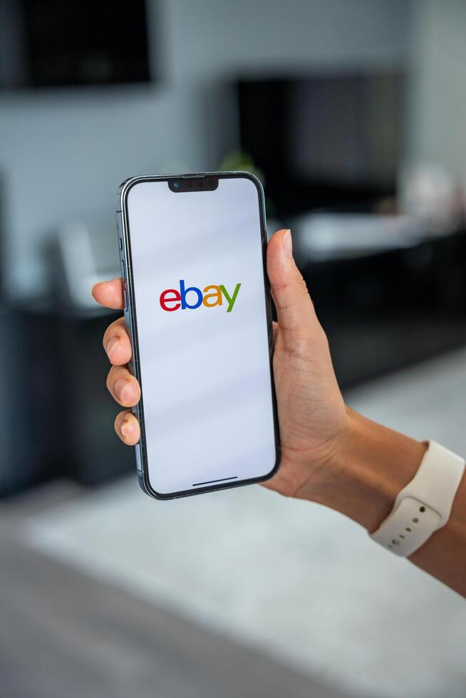 Prague, Czech republic - May 2, 2024. Woman holding iPhone with logo of application Ebay on the screen, using mobile application . High quality photo