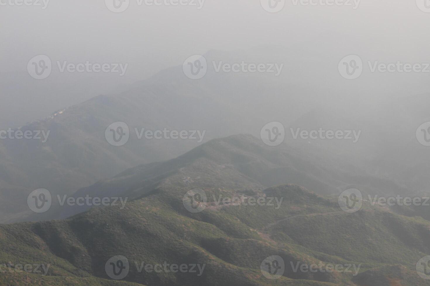 A plane flying over a mountain range with fog photo