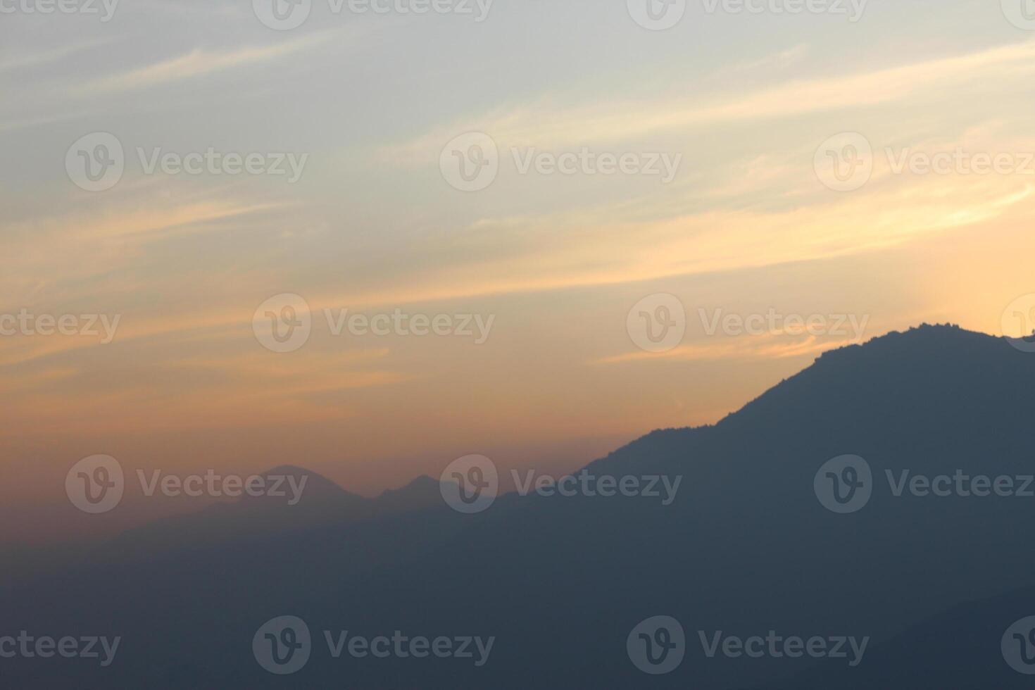 A plane flying over a mountain at sunset photo