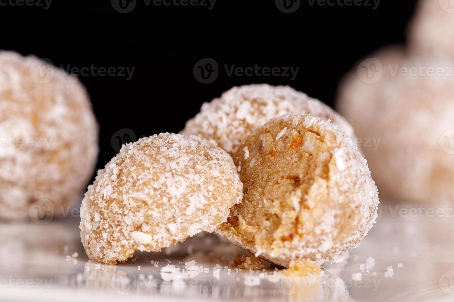 Beautiful sweets with coconut on a white plate on a black background close up photo