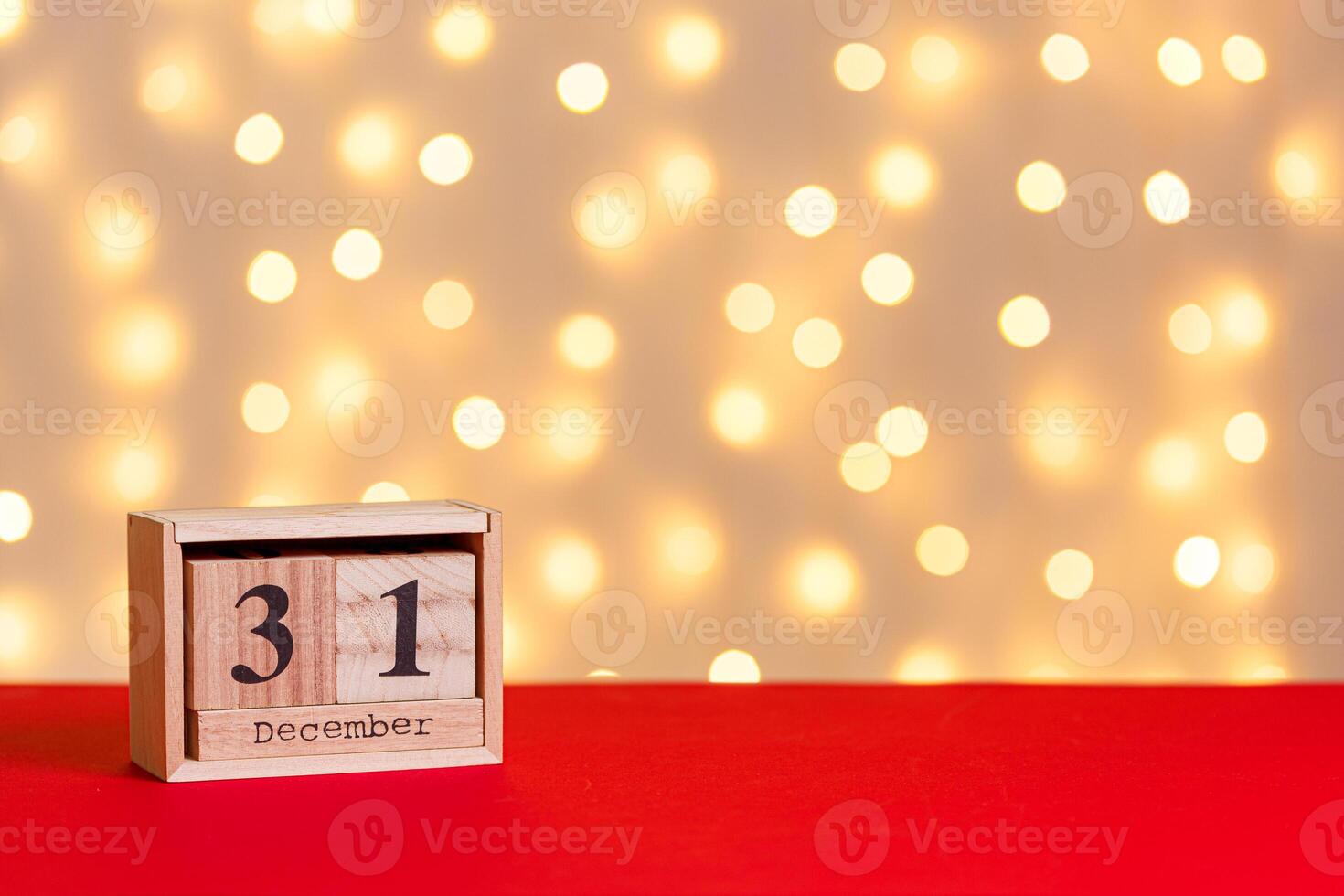 wooden calendar 31 december on red background and lights background close up photo