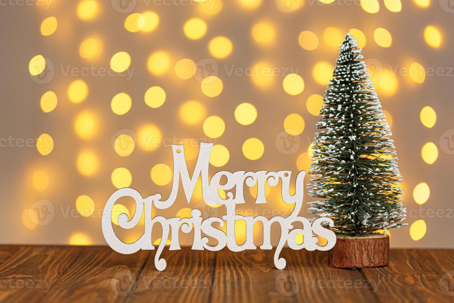 Christmas tree and the inscription Merry Christmas against the background of blurry lights close up photo