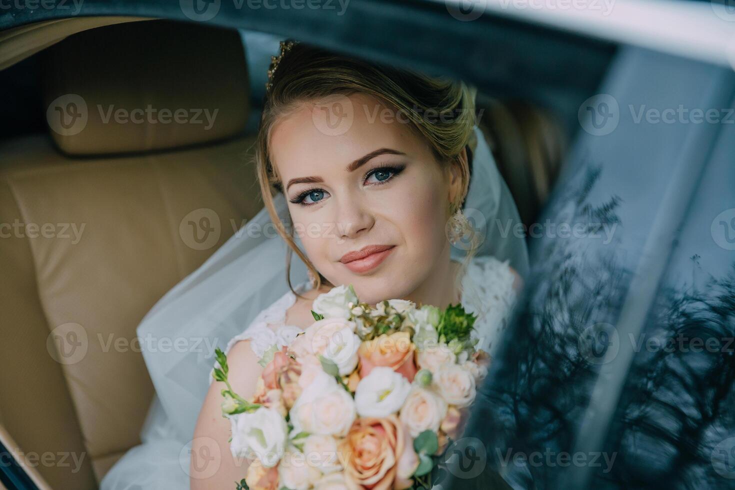 A bride is sitting in a car with a bouquet of flowers in her lap. photo