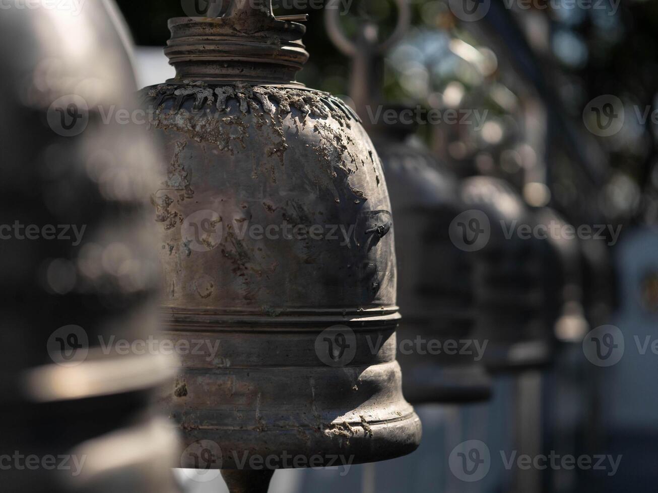 Traditional antique bells hang in an outdoor temple in Thailand. Close-up of beautiful bells lined up in a Buddhist temple or place in Thailand. Calm and believe. photo