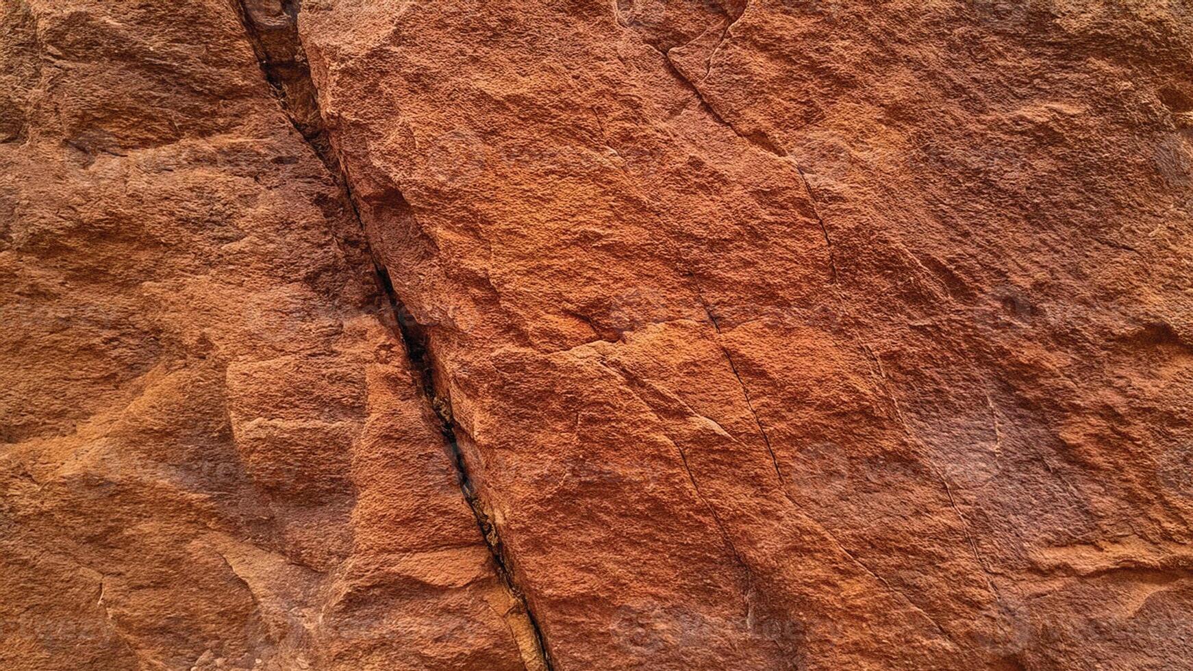 Textured orange sandstone with pronounced ridges and fissures, showcasing rugged geological formations perfect for backgrounds, architectural designs, and natural stone patterns. photo