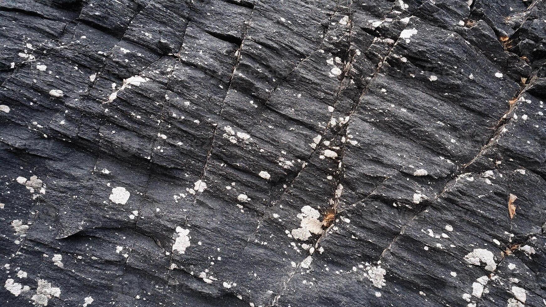 Rough slate rock surface texture with prominent cracks and deep grooves, perfect for natural geological designs, stone backgrounds, and rugged architectural surface inspirations photo