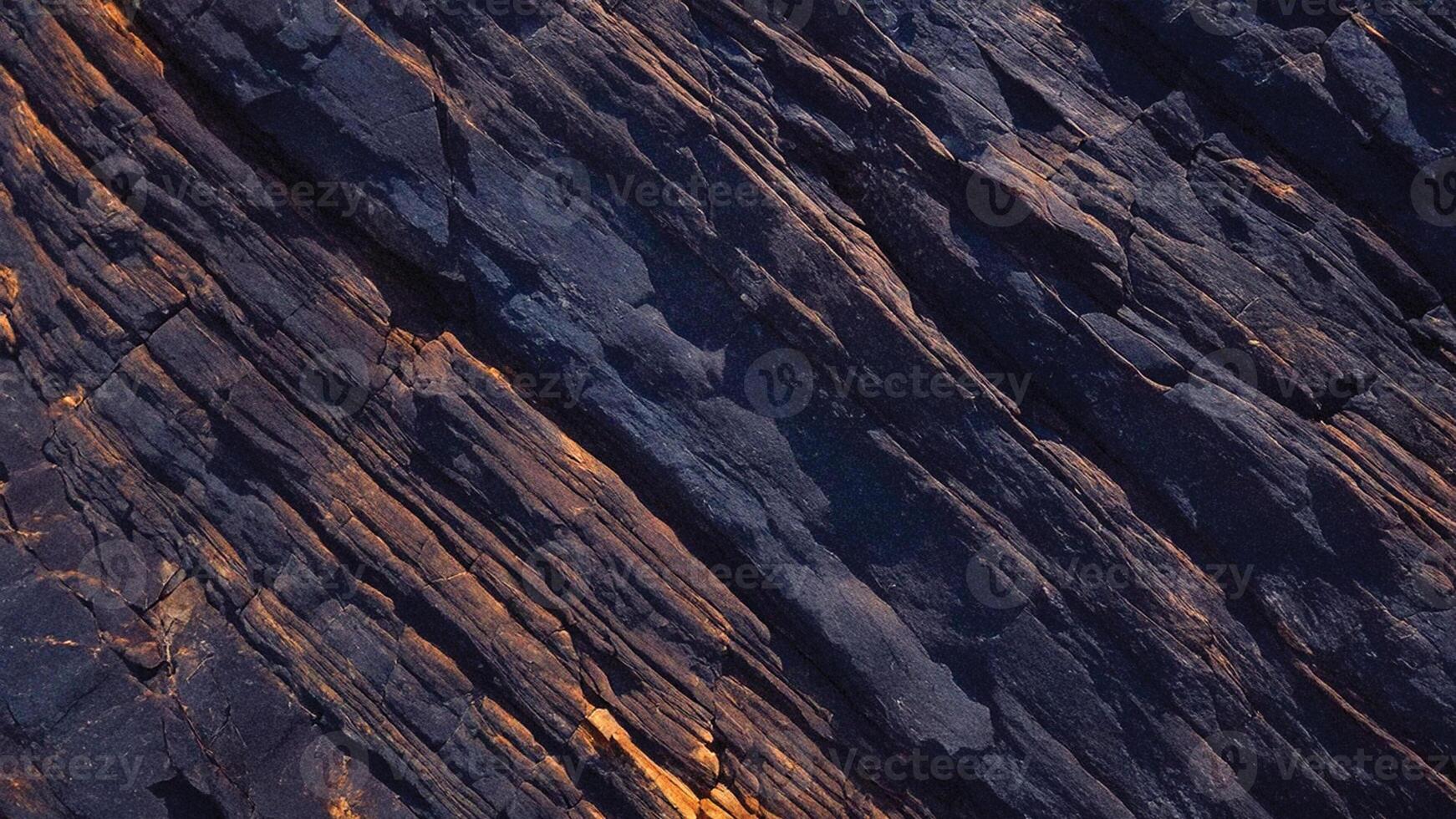 Rough slate rock texture with rust accents and deep fissures, ideal for geology-themed backgrounds, stone designs, and architectural elements with organic patterns photo