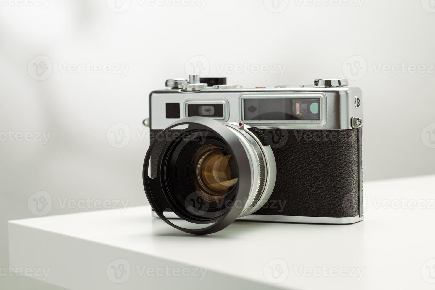 A vintage film camera sits elegantly on a white surface, showcasing its timeless design. photo