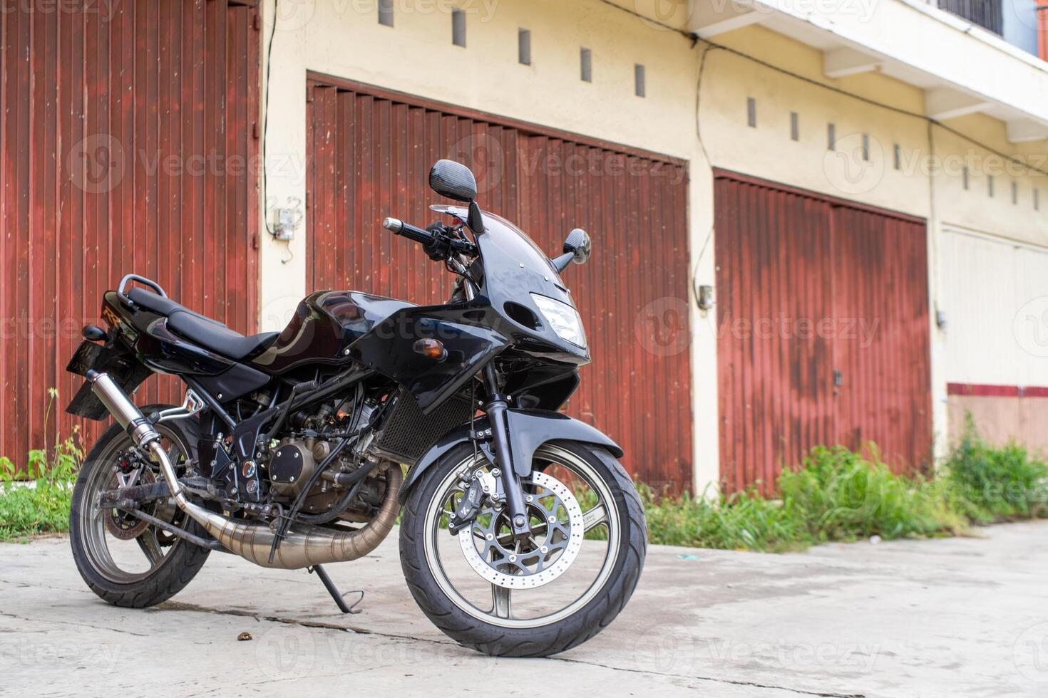 Modern black motorcycle parked in front of a rustic red warehouse, perfect for themes of adventure and modern lifestyle photo