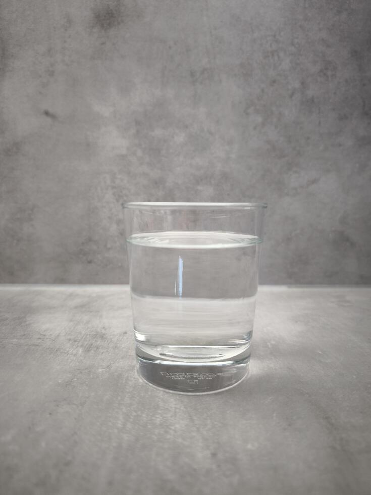 Prague, Czech republic - January 1, 2025. Transparent drinking water resting in Ikea glass on concrete background, hydration and wellness concept. Source of life, World Water Day copy space photo