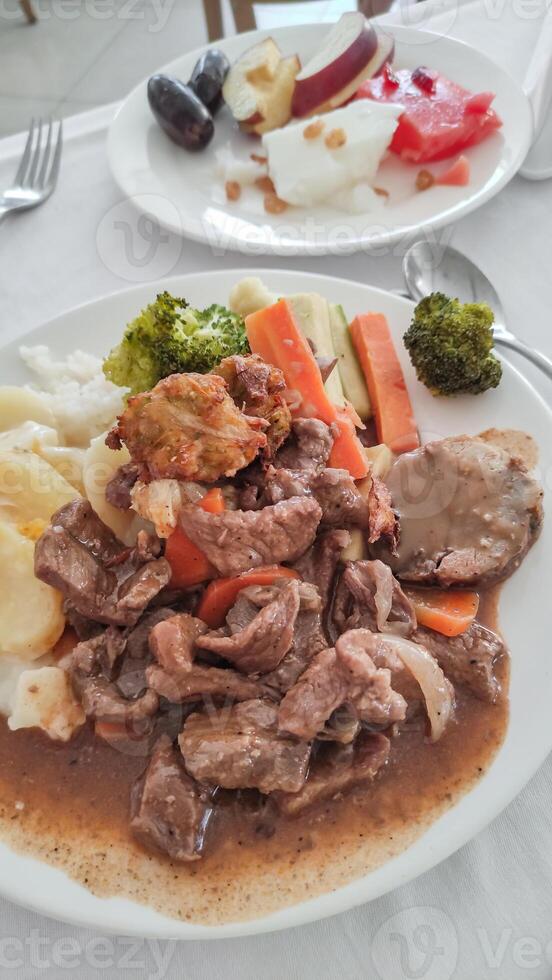 Beef stew with mashed potatoes, vegetables and fried dumplings served with fruit salad in an egyptian sataya resort photo