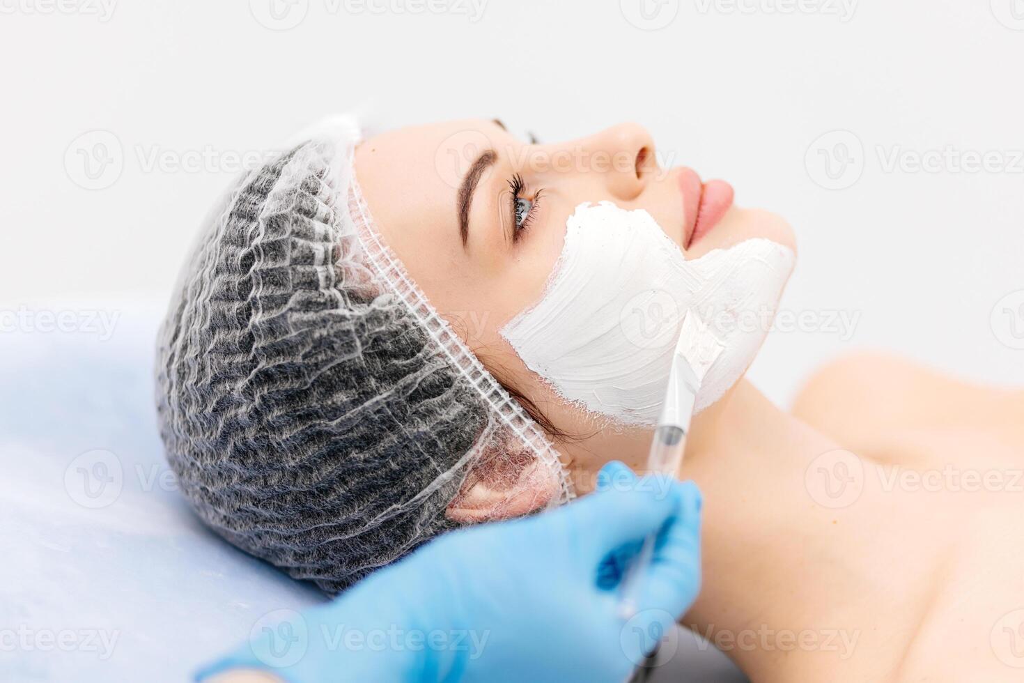 Caucasian middle-aged woman receiving a moisturizing facial mask applied by a beautician in a spa setting. Relaxing facial treatment at a spa for glowing skin rejuvenation photo