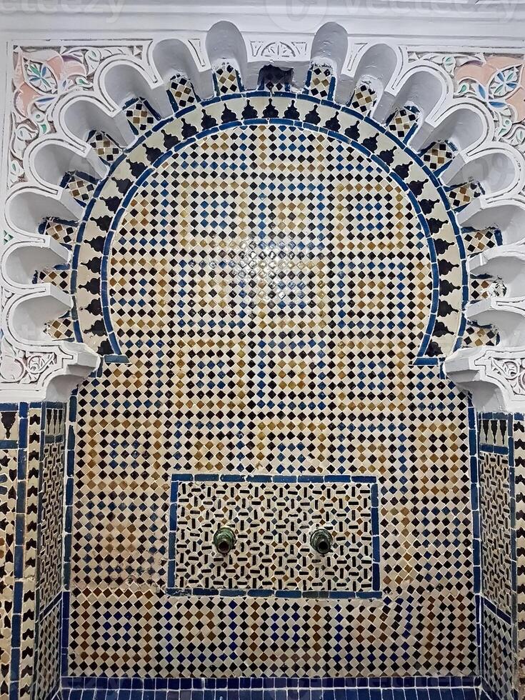A fountain adorned with intricate Moroccan Zellige tiles crafted geometric patterns in vibrant colors and forms, reflecting the exceptional skill of Moroccan craftsmen who mastered their craft photo