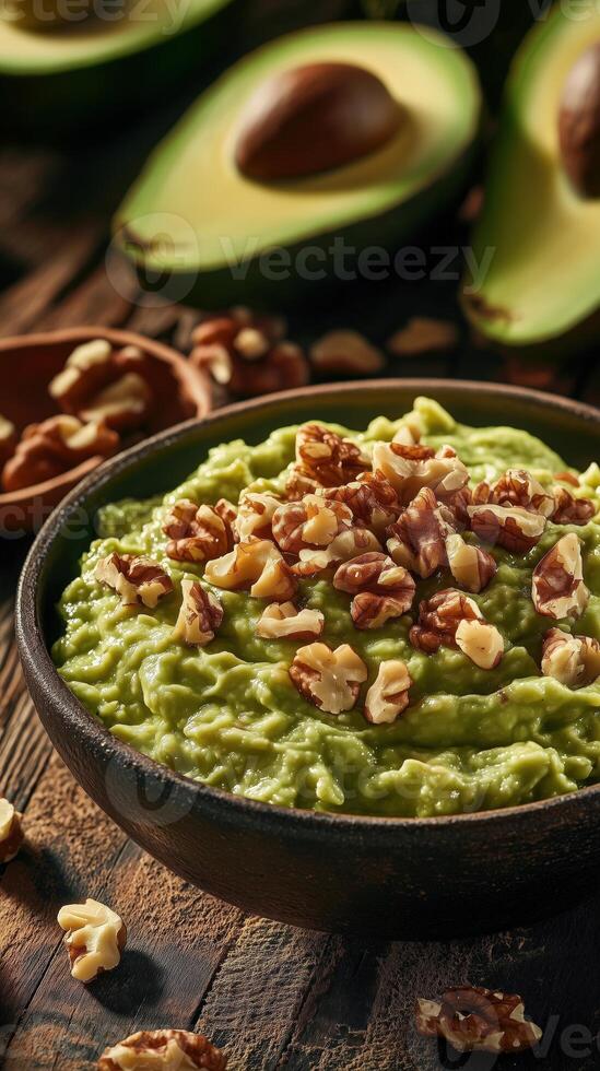 Bowl of creamy guacamole topped with crunchy walnut pieces, fresh avocado and walnut photo