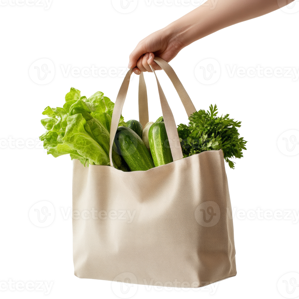 A hand holds a beige tote bag filled with fresh green vegetables png