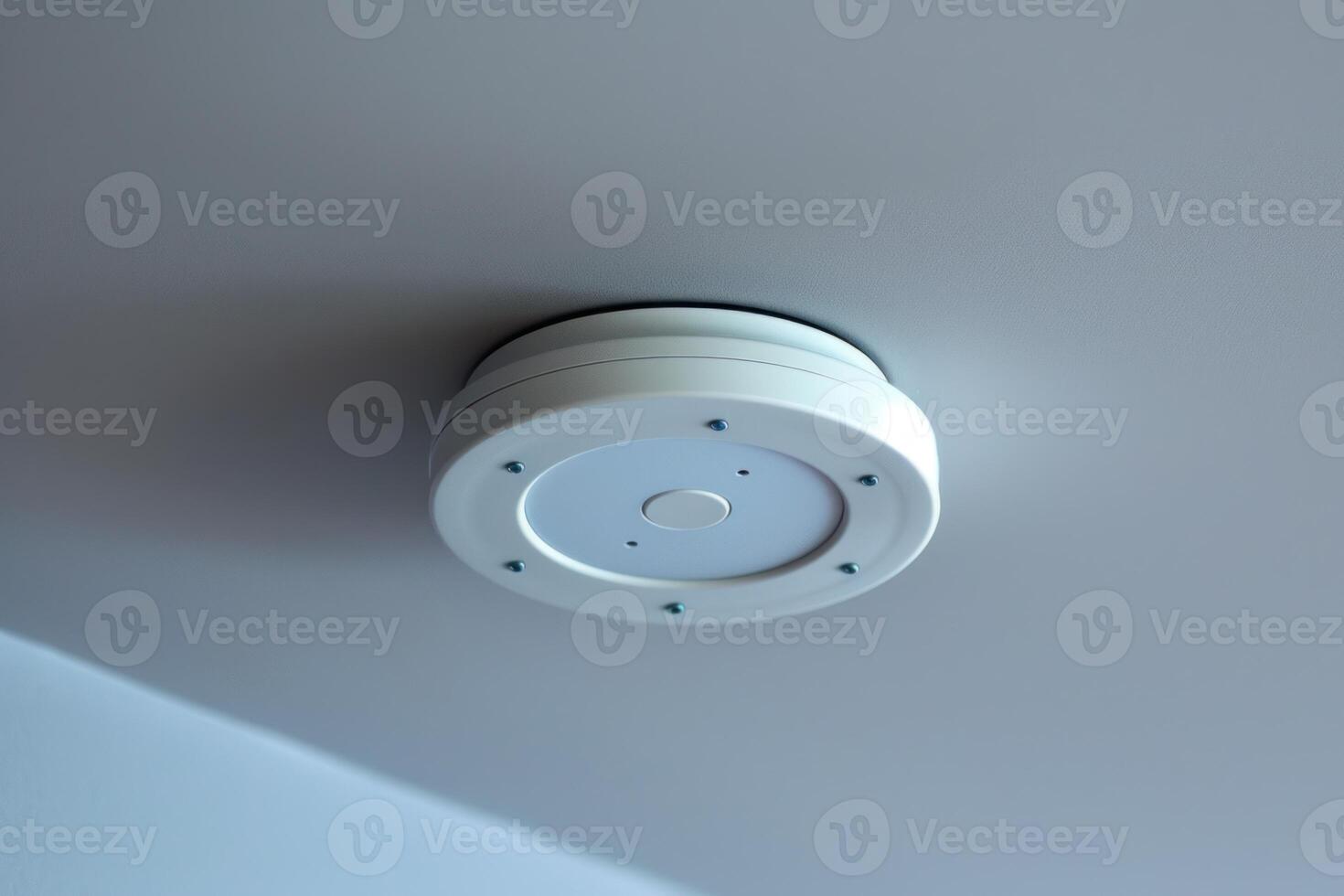 A white smoke detector mounted on the ceiling photo