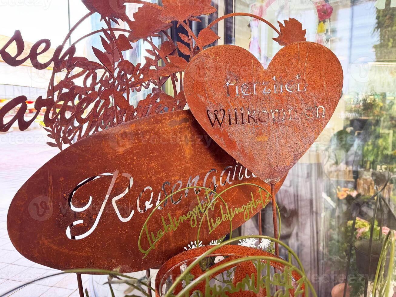 Rustic metal welcome sign in garden with heart and leaves design photo