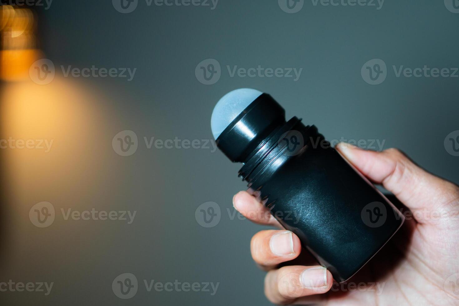Hand holding black roll-on deodorant photo
