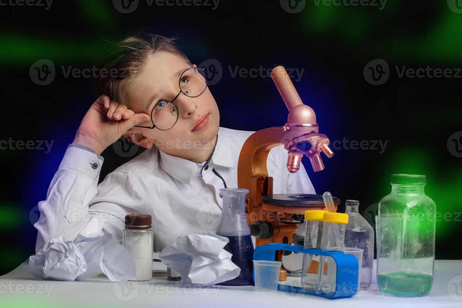 A boy scientist researcher with a microscope is thinking about ideas in the laboratory. photo