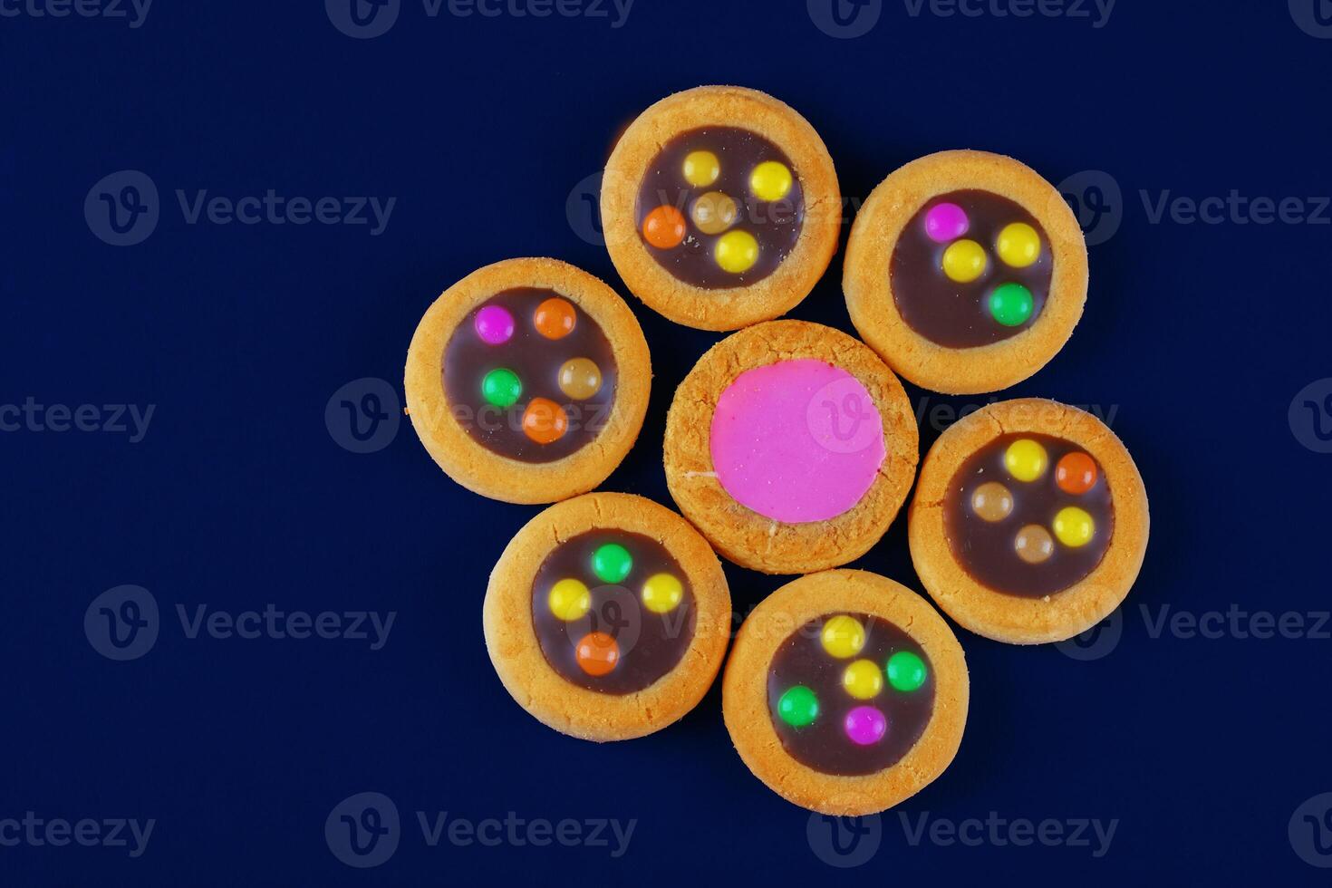 A creative sweet dessert. Cookies with chocolate filling and pink glaze on a dark blue background in the form of a flower. photo