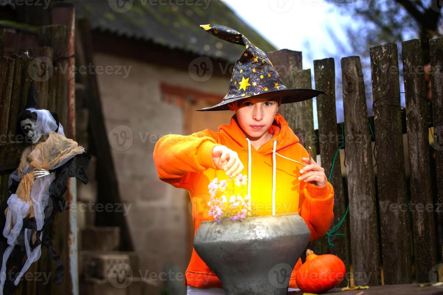 Halloween a child with a magic bowler hat in a sorcerer's hat performs witchcraft against the background of an old creepy house. photo