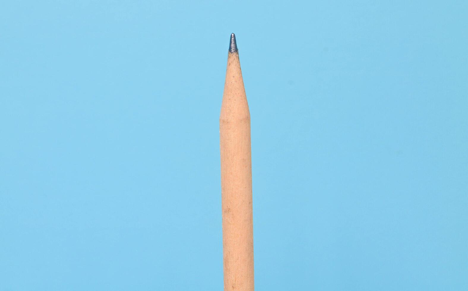 One classic light brown wooden pencil isolated on a blue background with copy space photo