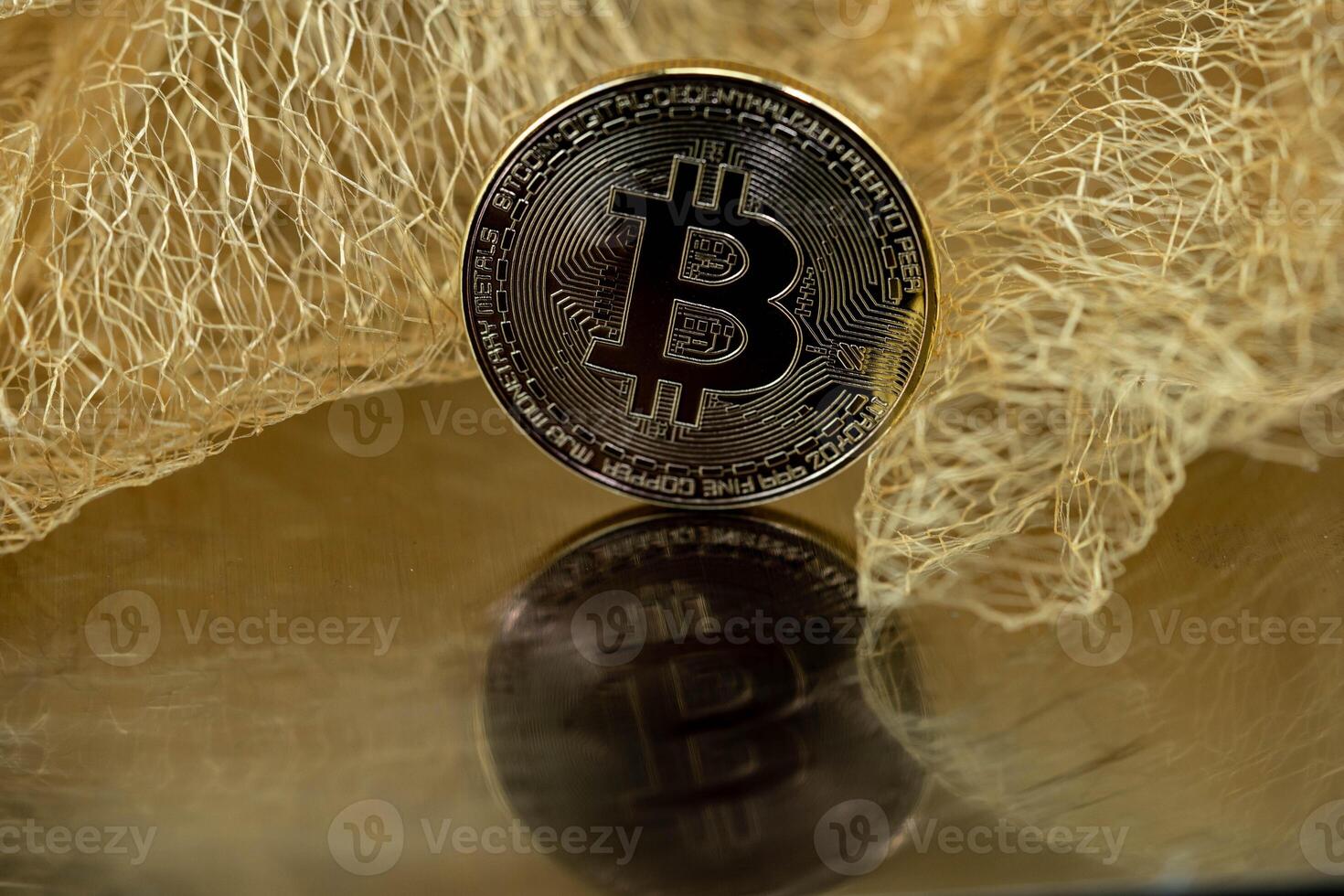 One Bitcoin with mirror image in front of a tile made of gold threads photo